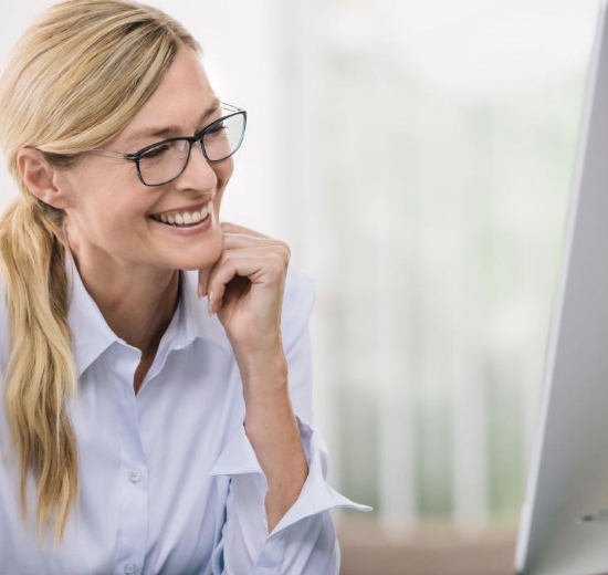 Frau mit Brille schaut in Bildschirm.